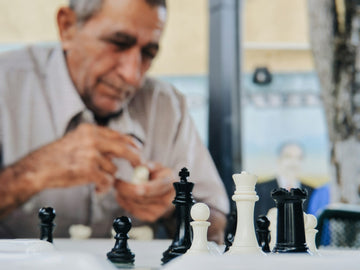 An older man considers a chess position - Juno Jo - Unsplash.